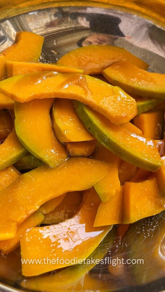 Drizzling olive oil and maple syrup on sliced squash