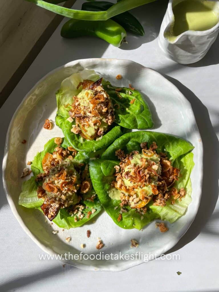 Overhead shot of lettuce cups filled with roasted squash, tofu crumble, nuts, and drizzled with serrano scallion lime dressing