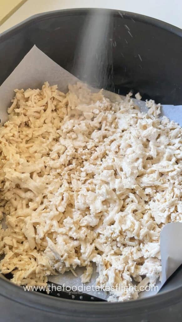 Shredded tofu on a parchment paper lined air fryer basket