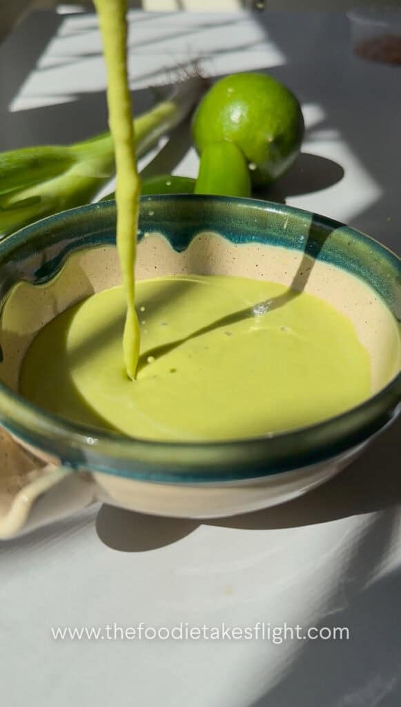 Pouring green scallion serrano dressing in a bowl