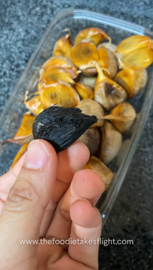 black garlic with papery skin partially removed to show caramelized cloves