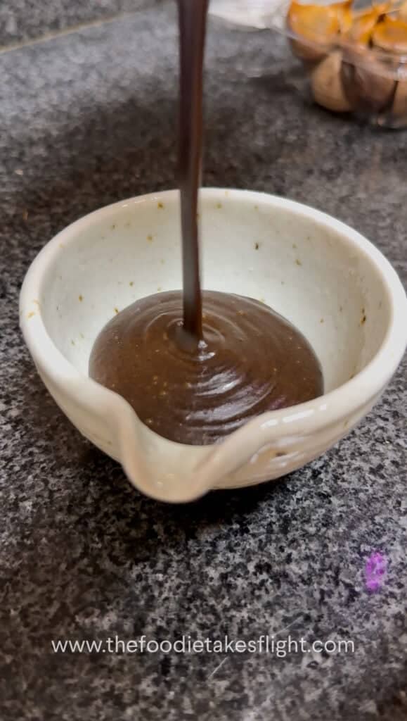 bowl of black garlic miso dressing showing its glossy, thick consistency.