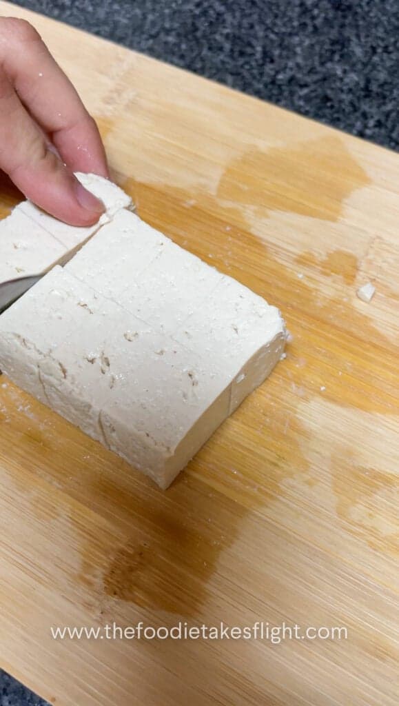 block of extra firm tofu being sliced into