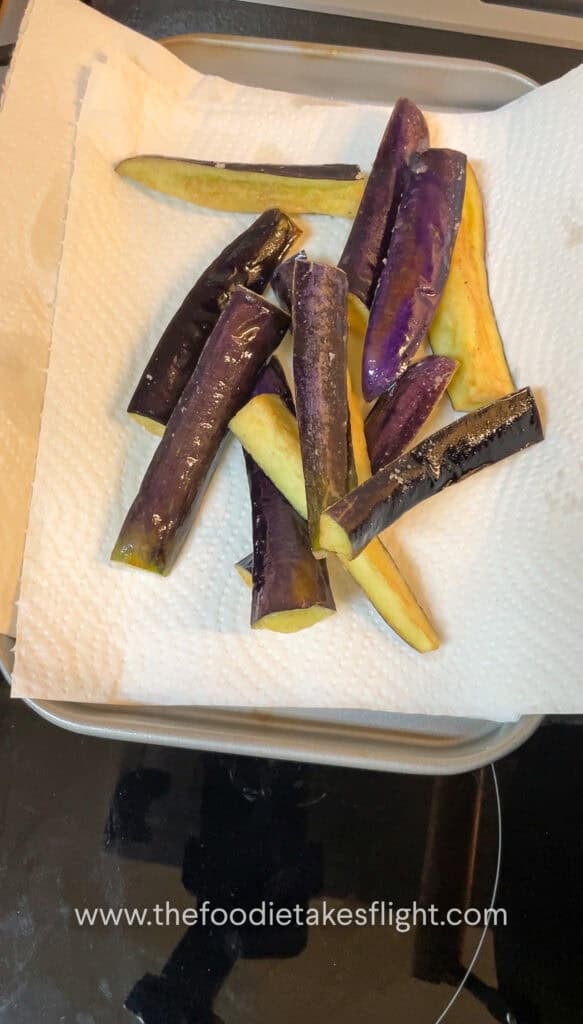 Lightly golden fried eggplant draining on a paper towel