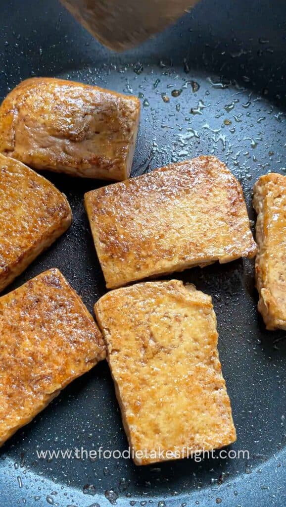Pan-fried golden tofu in a skillet