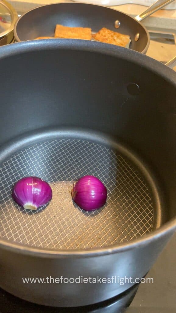 Red onion halves charring in a soup pot