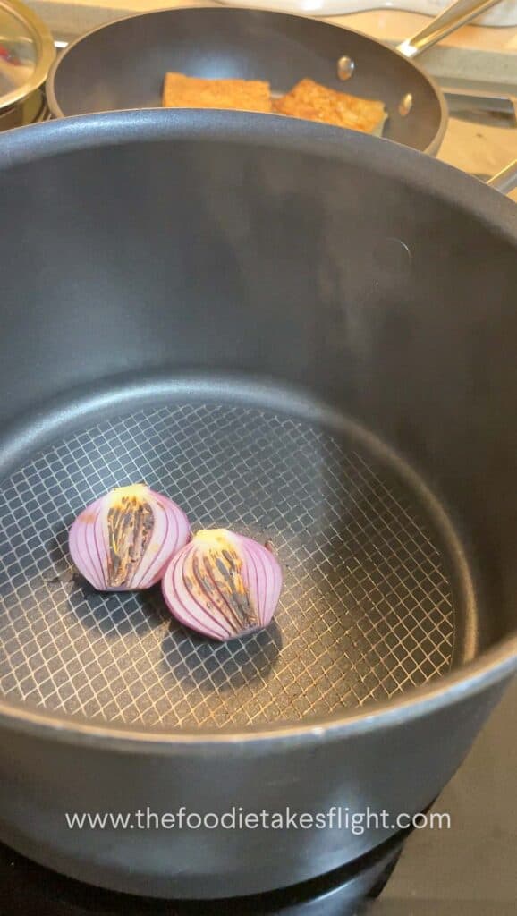 Red onion halves charring in a soup pot