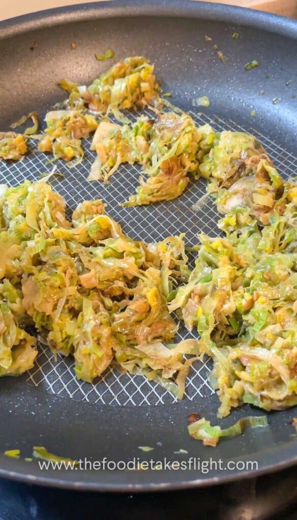 Thinly sliced leeks cooking in a pan until soft and golden brown.