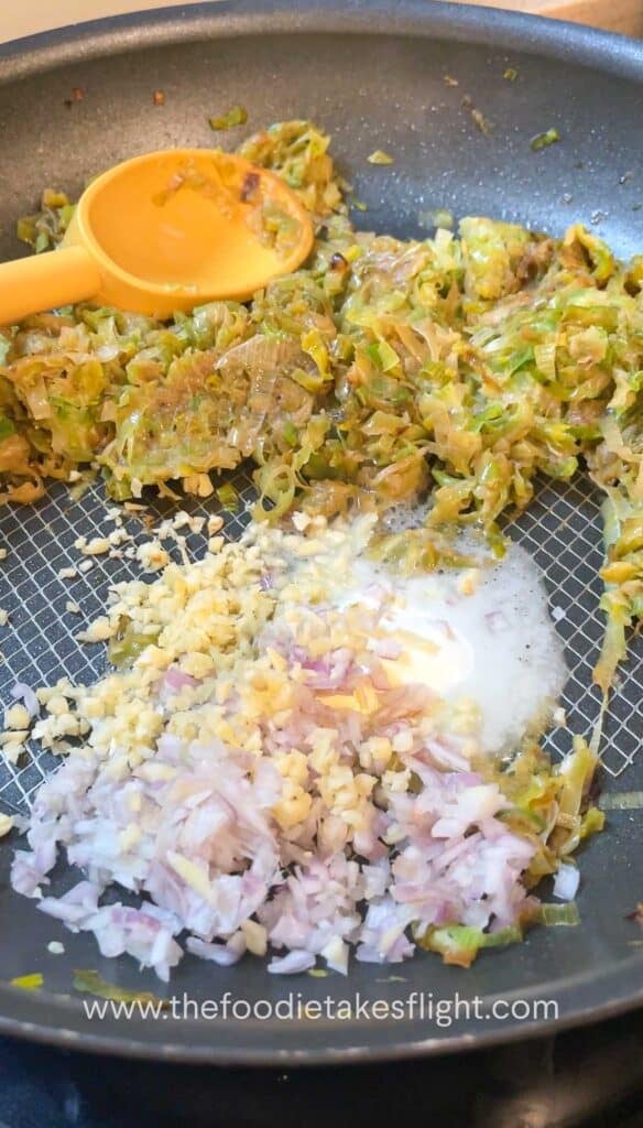 Caramelised leeks pushed to the side of the pan with shallots and garlic sautéing beside them