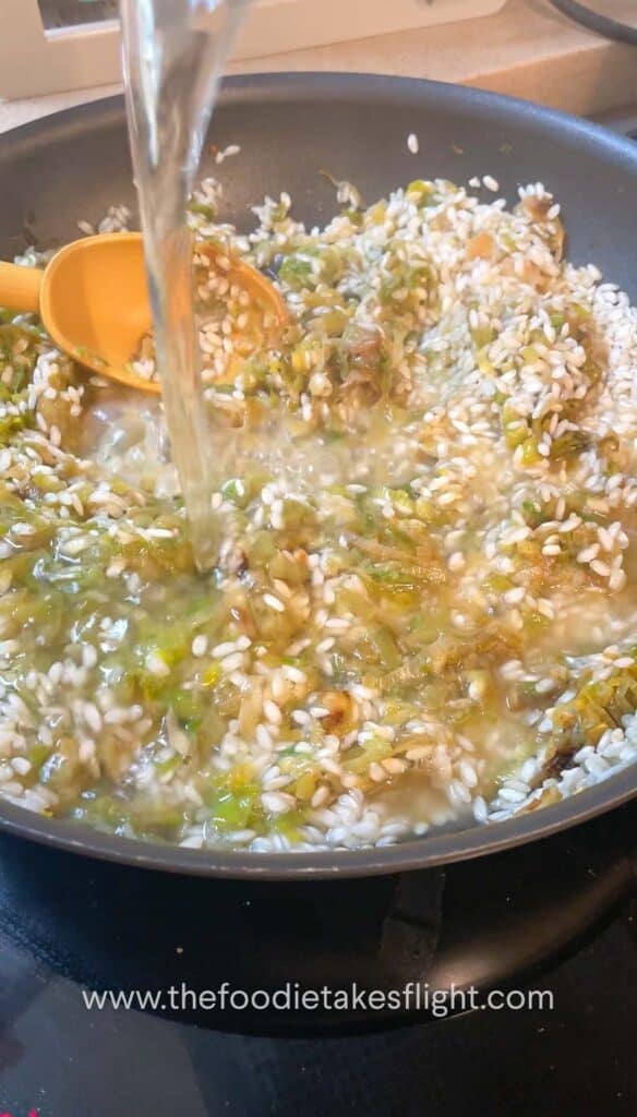 adding vegetable broth to pan of risotto