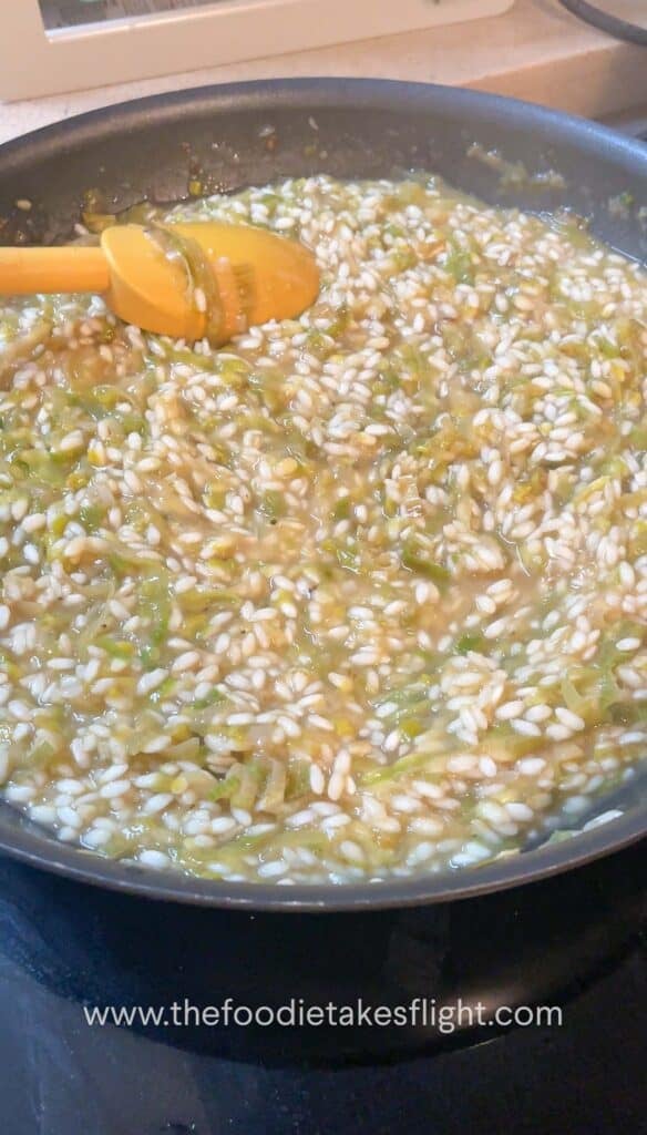 grains of arborio rice slowly cooking down in a pan