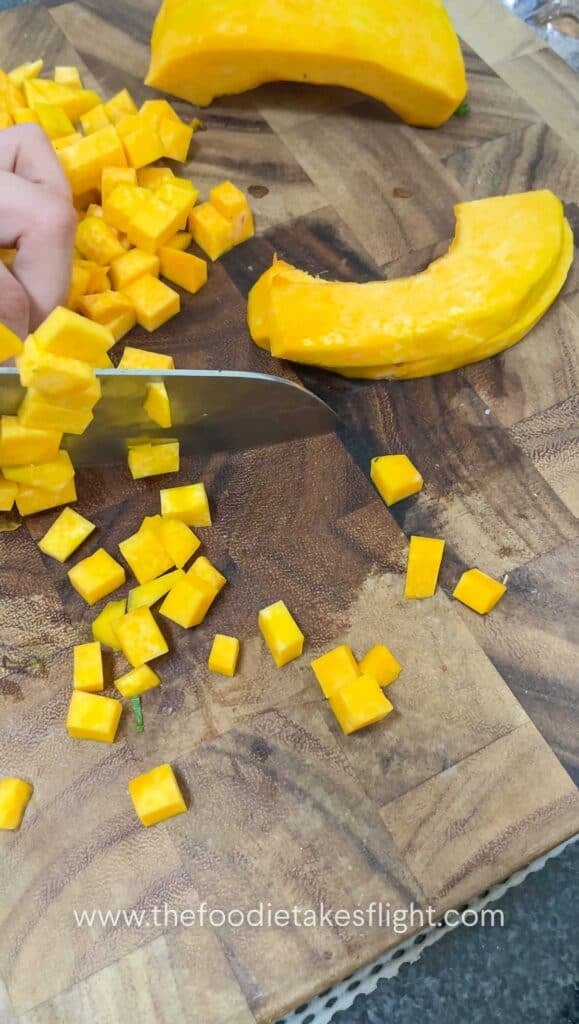 dicing pumpkin on a wooden cutting board