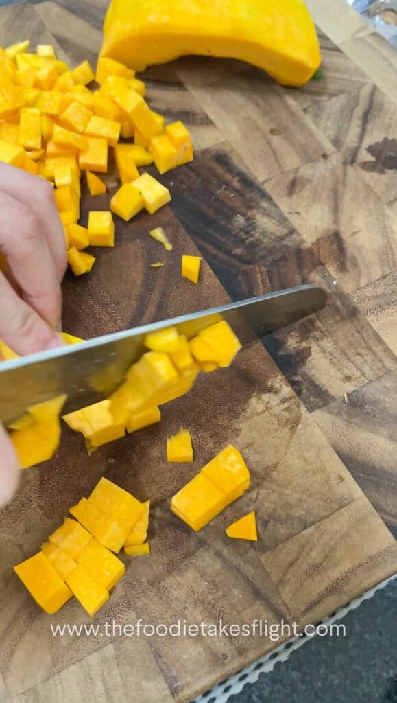 dicing pumpkin on a wooden cutting board