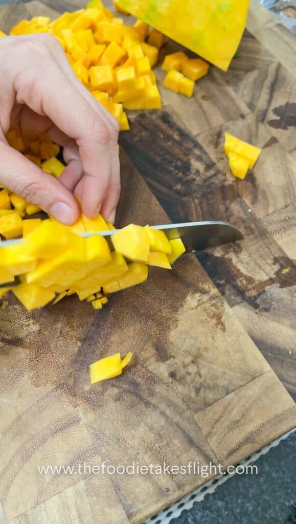 dicing pumpkin on a wooden cutting board