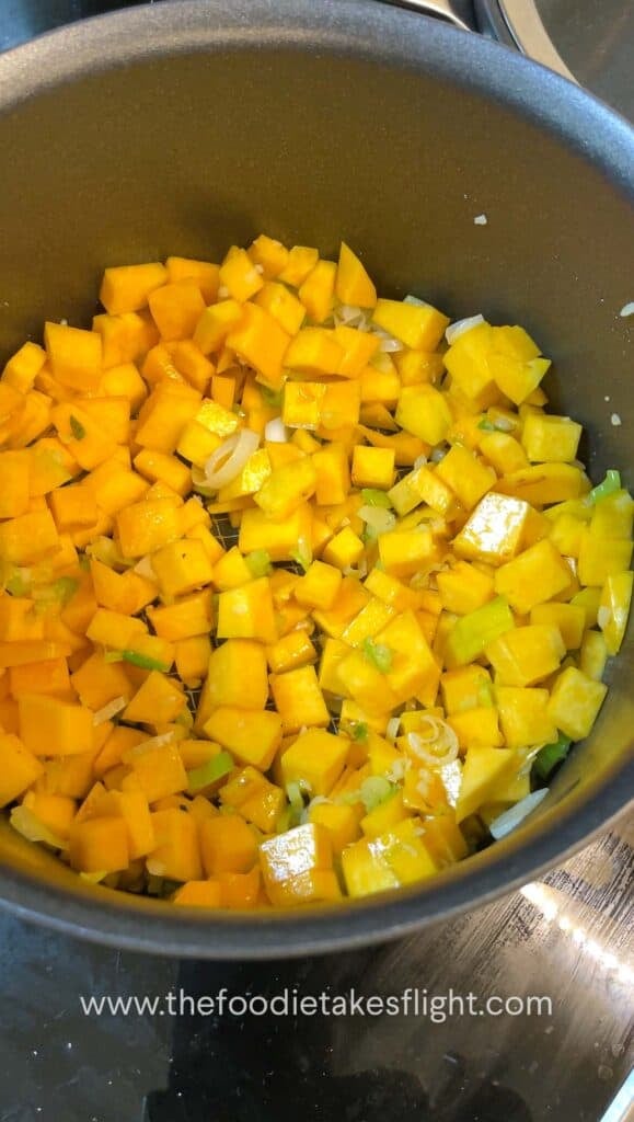 Pumpkin cubes cooking in a pot until lightly charred on the edges