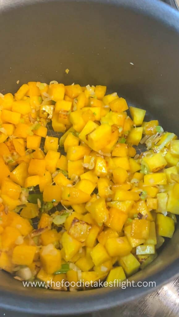 Pumpkin cubes cooking in a pot until lightly charred on the edges