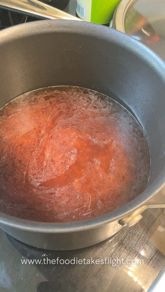 Rice, soy sauce, and mushroom broth being stirred together in a pot
