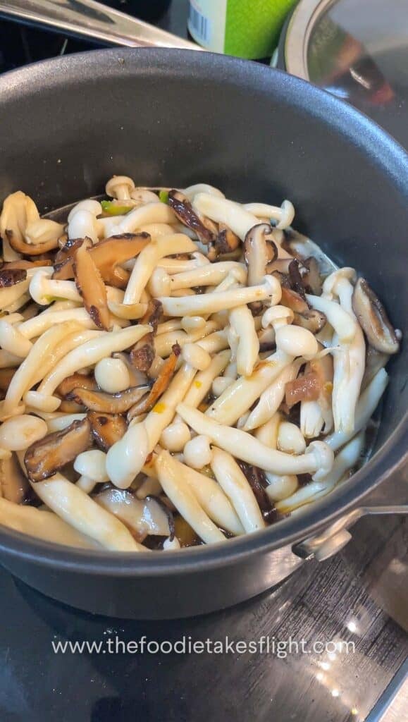 Layered mushrooms and pumpkin on top of seasoned rice before cooking