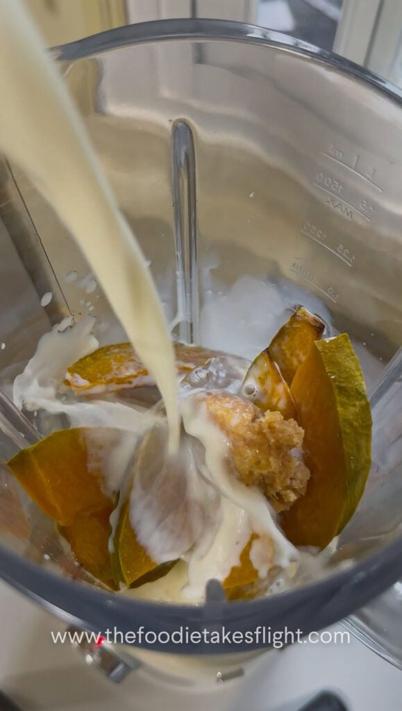 adding plant based dairy free milk into a blender with roasted pumpkin