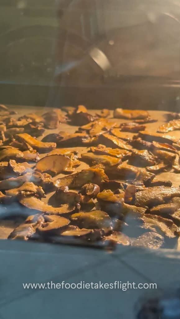 Shiitake mushroom slices coated in smoky seasoning on parchment paper ready to bake