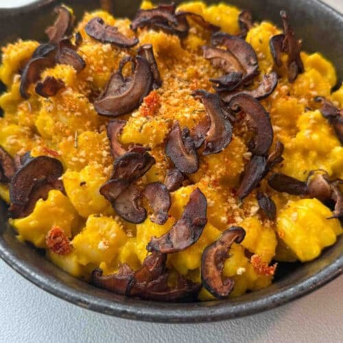 Finished pumpkin miso pasta garnished with chili breadcrumbs and shiitake bacon on a g