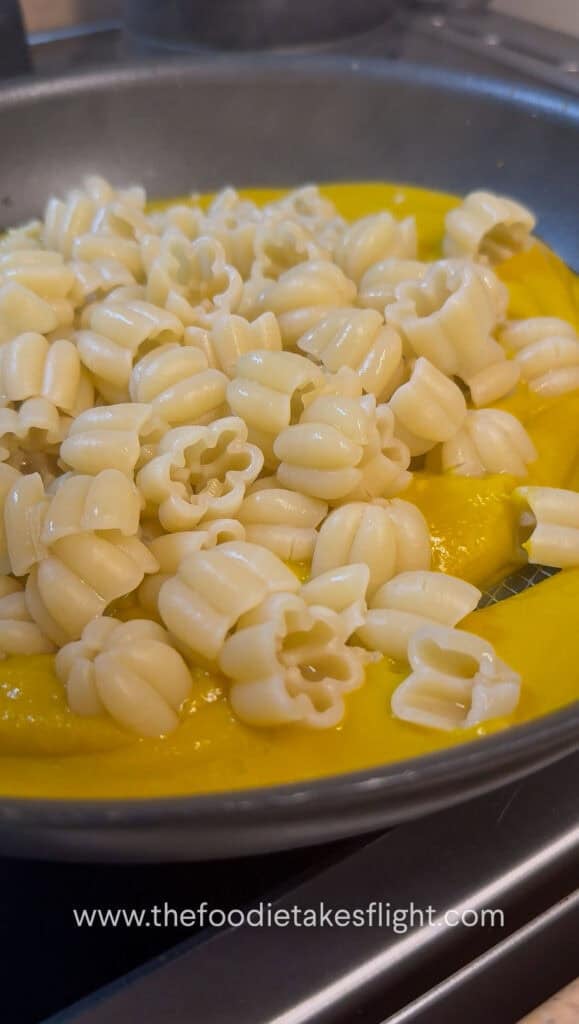 Tossing cooked pasta in creamy pumpkin miso sauce