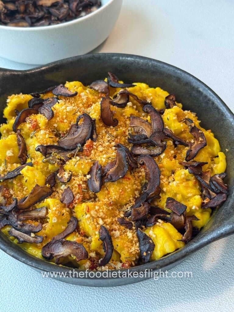 Finished pumpkin miso pasta garnished with chili breadcrumbs and shiitake bacon on a g