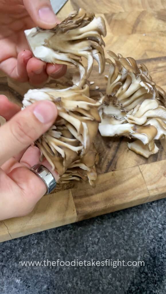 breaking apart maitake mushrooms
