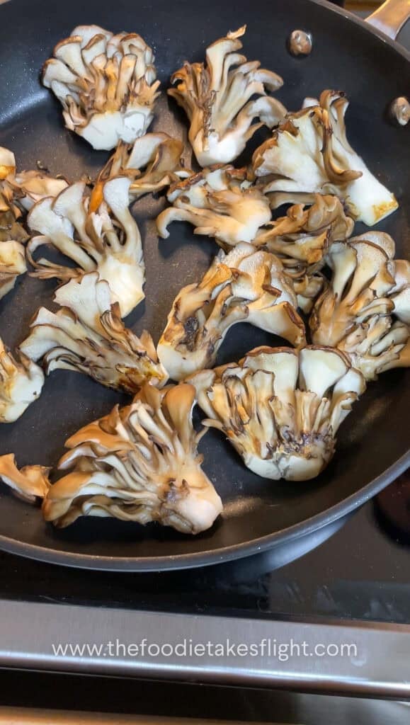 Maitake mushrooms searing in a pan