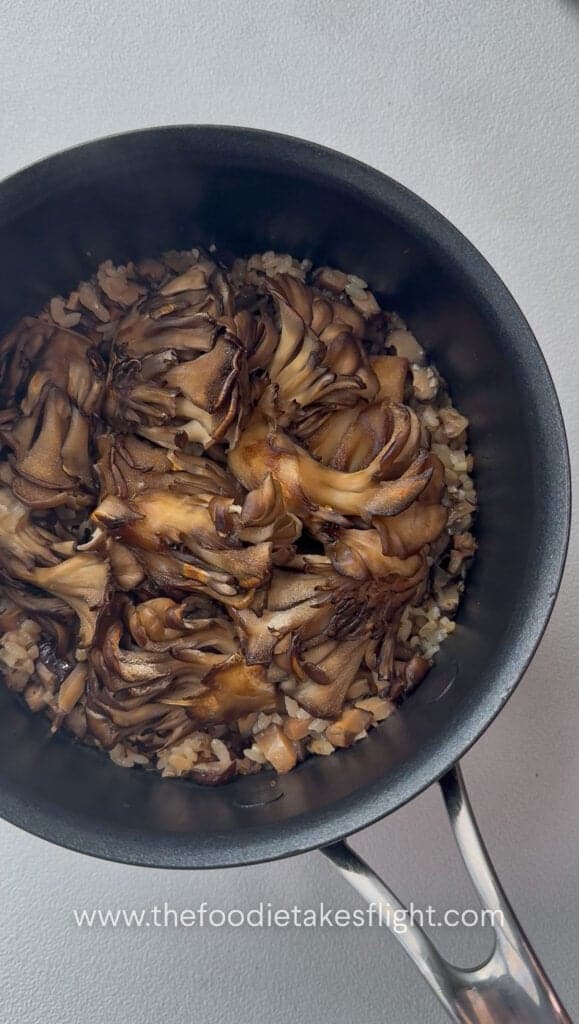 overhead shot of pot of rice topped with maitake mushrooms