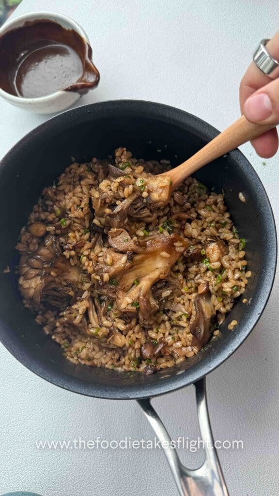 rice pot filled with glazed maitake mushrooms, black garlic miso sauce and chives