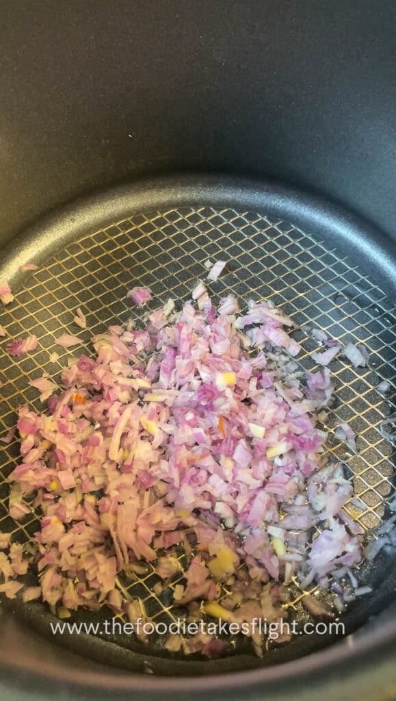 Shallots sautéing in a pot with neutral oil