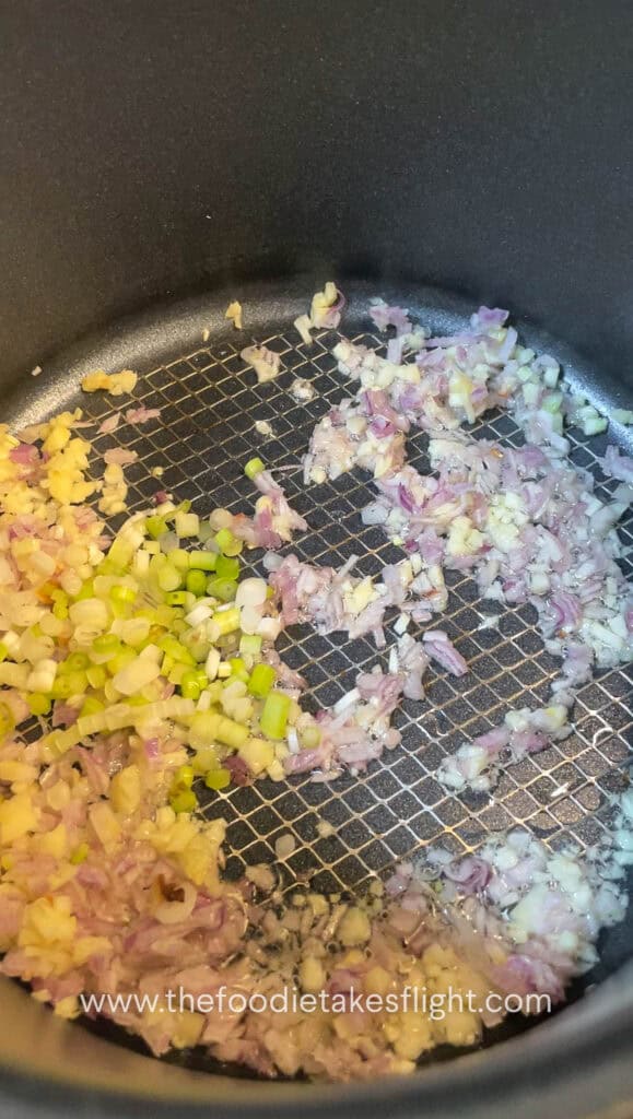 Shallots and garlic sautéing in a pot with neutral oil