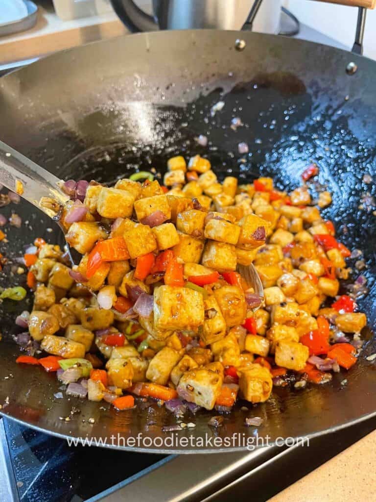 Pan-fried tofu being tossed with oyster sauce and seasonings
