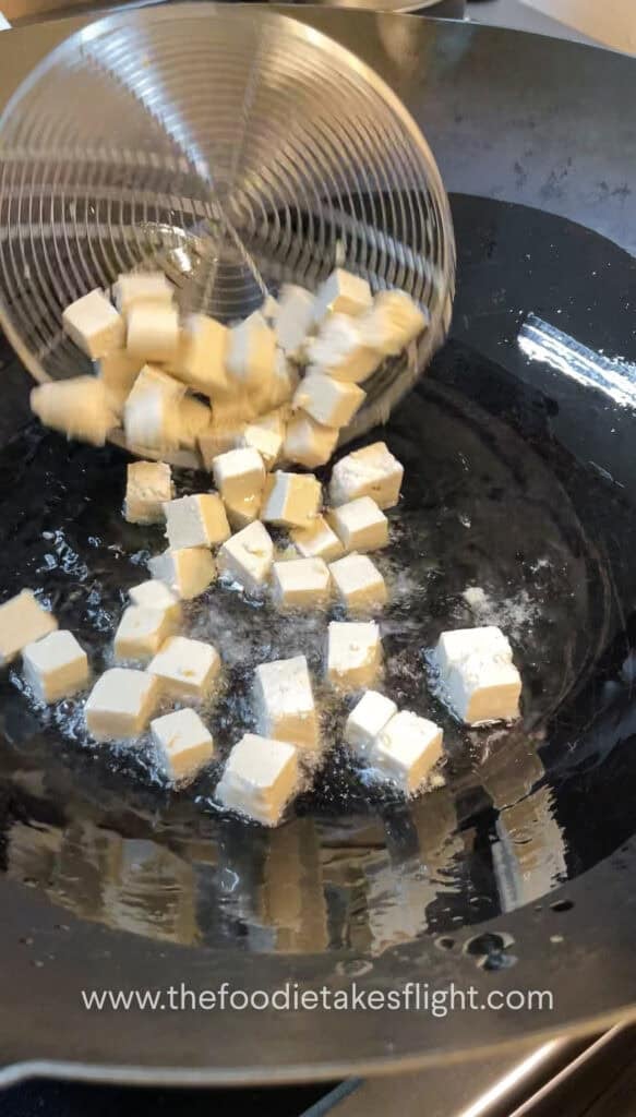 Cubed tofu frying in a wok until golden and crisp