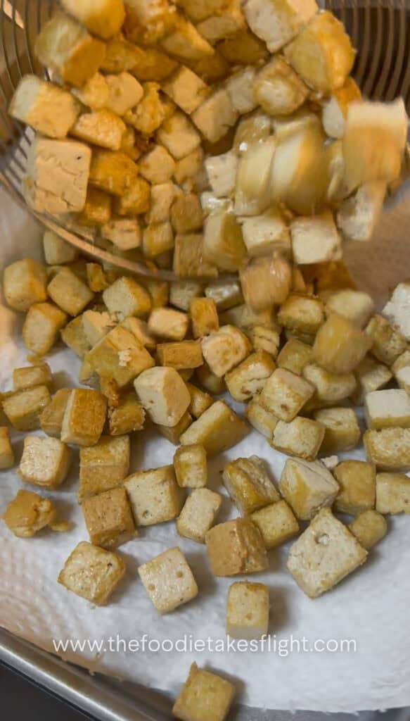 golden brown cubes of tofu fried in a wok