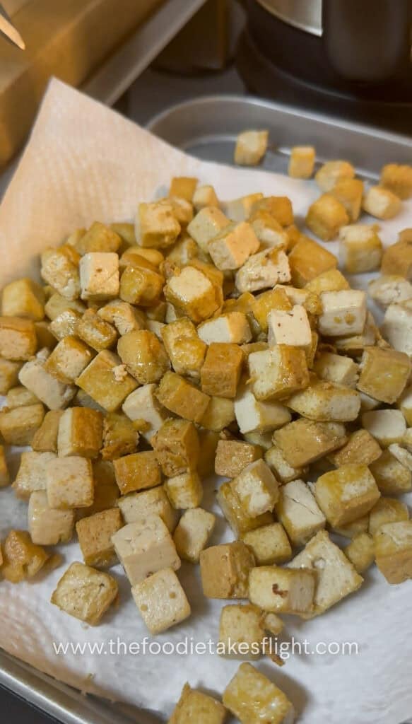 golden brown cubes of tofu fried in a wok