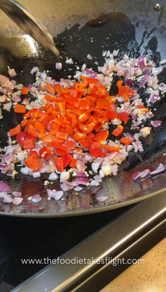 Diced onions, garlic, and bell peppers sautéing in a wok
