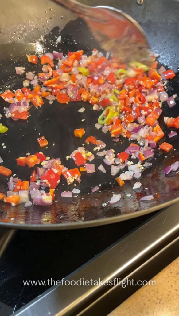 Diced onions, garlic, and bell peppers sautéing in a wok
