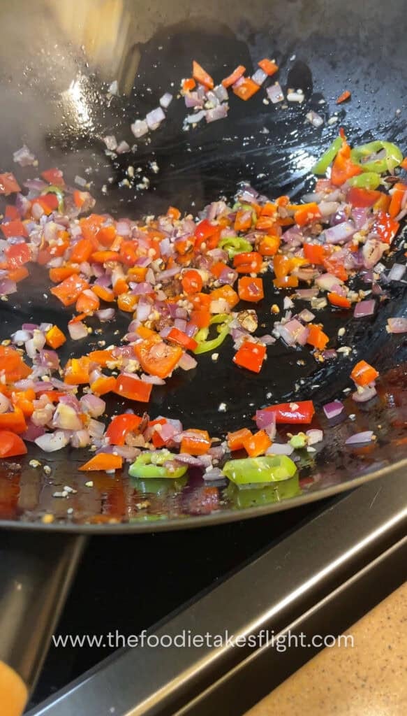 Diced onions, garlic, and bell peppers sautéing in a wok