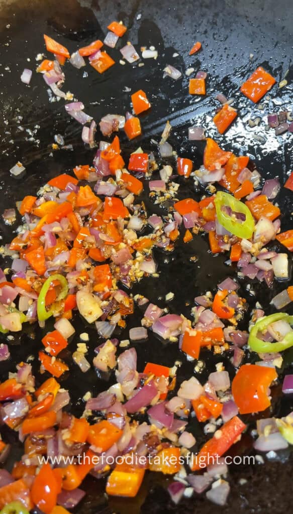 Diced onions, garlic, and bell peppers sautéing in a wok