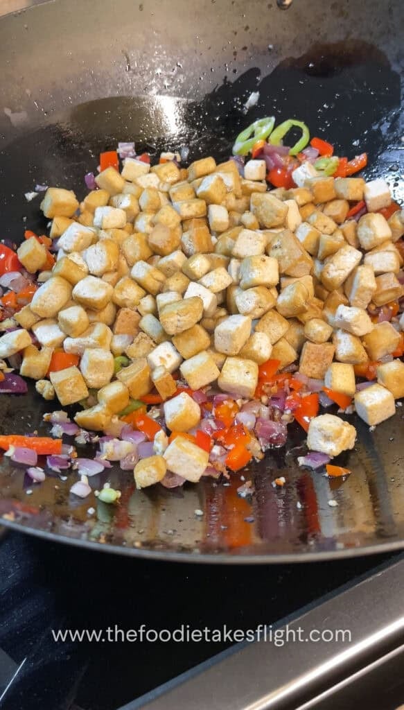 Pan-fried tofu being tossed with oyster sauce and seasonings