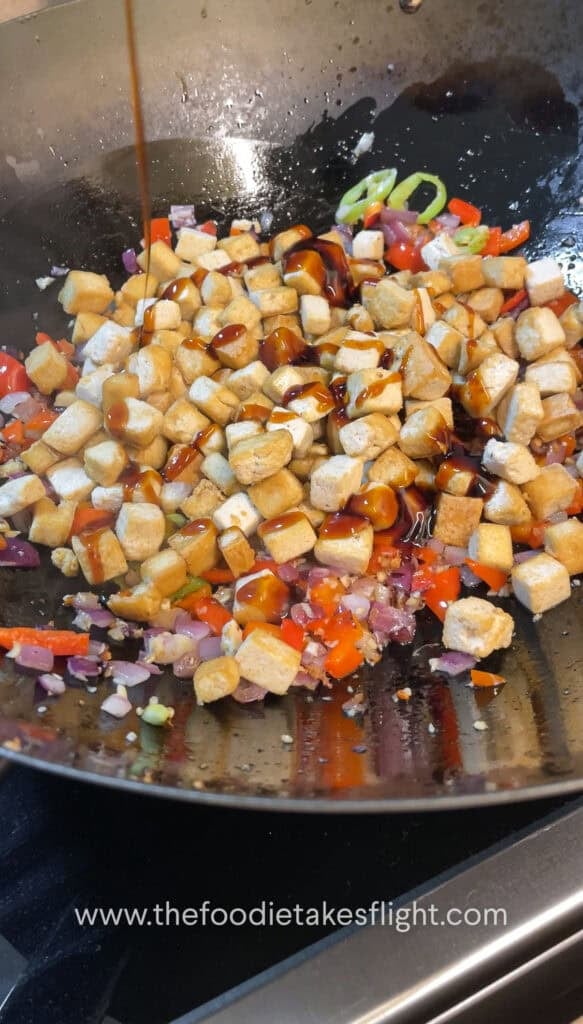 Pan-fried tofu being tossed with oyster sauce and seasonings