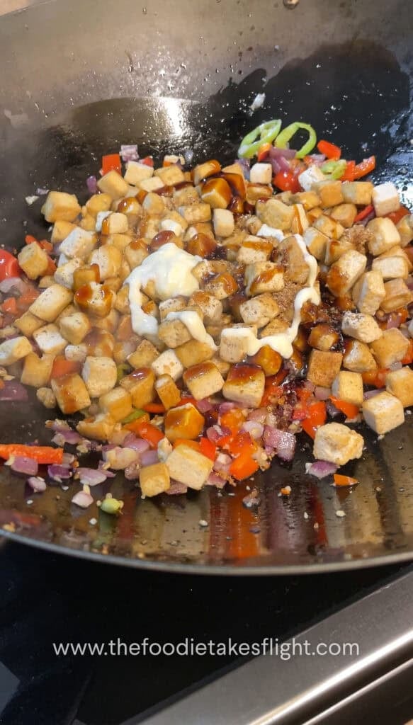 Pan-fried tofu being tossed with oyster sauce and seasonings