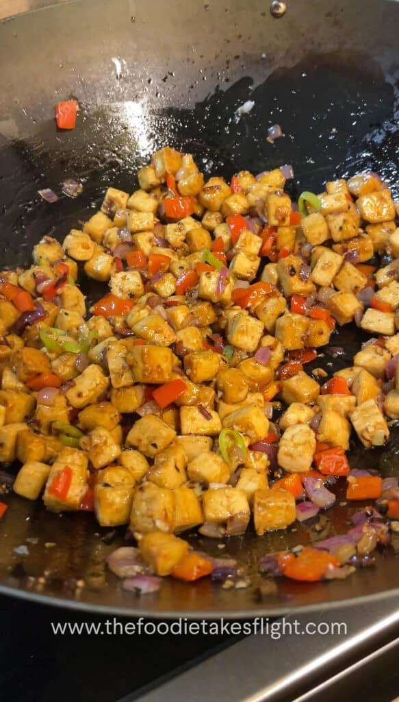 Pan-fried tofu being tossed with oyster sauce and seasonings