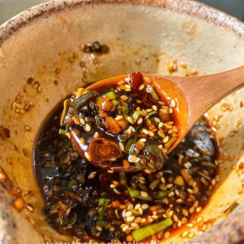 Small bowl of sweet and spicy all-around dipping sauce with visible garlic, scallions, and chili oil