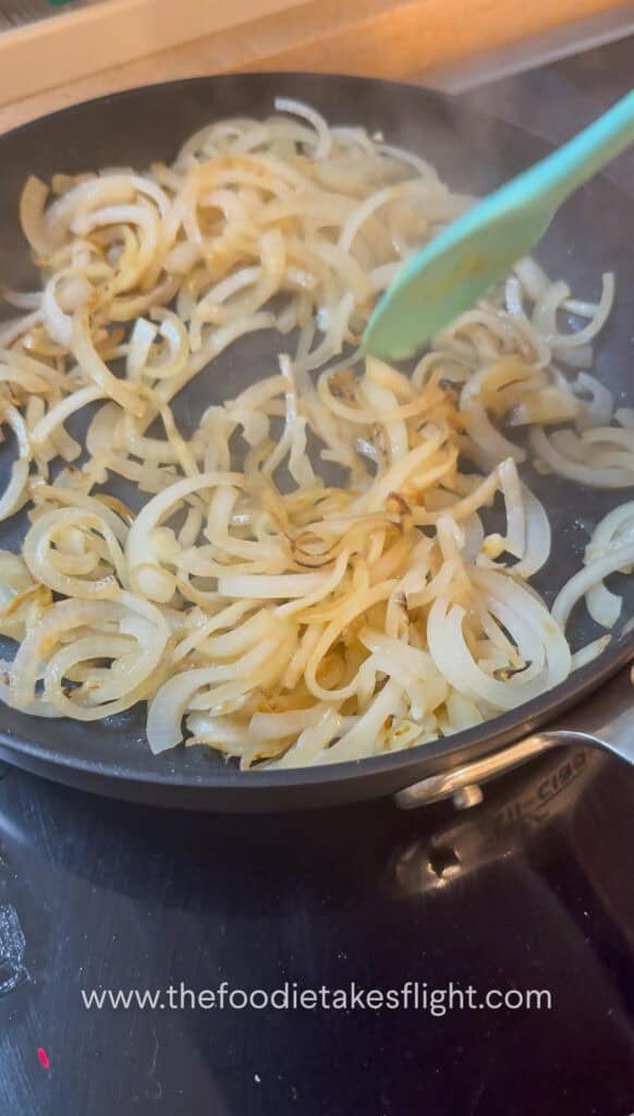 Thinly sliced onions caramelising in a skillet until deep golden brown
