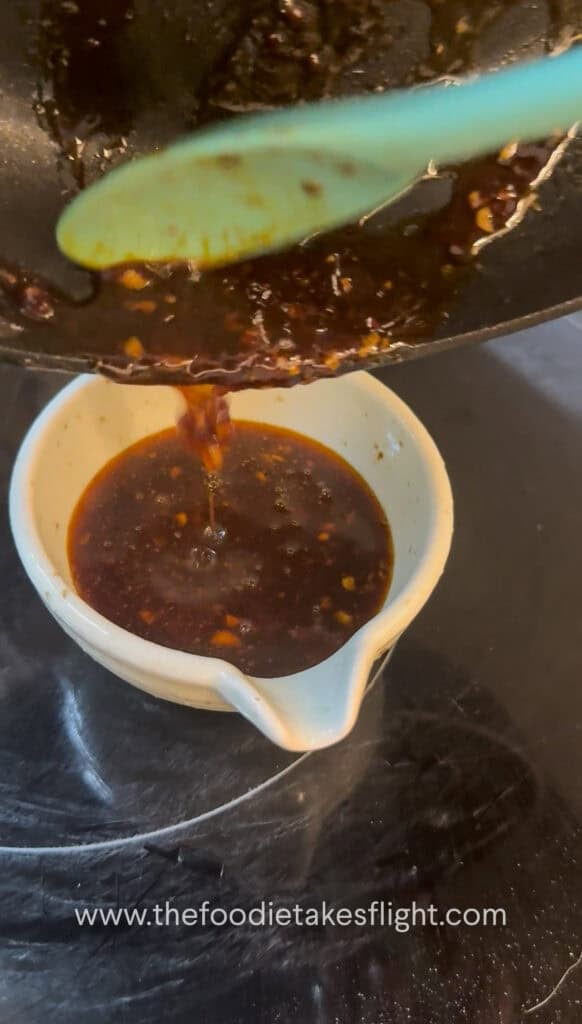 Pouring gochujang butter sauce into a small bowl