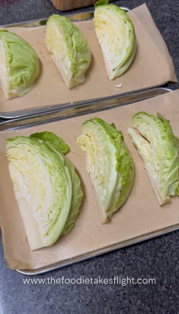 Raw cabbage sliced into wedges and arranged on a baking tray