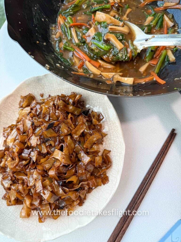 Gravy in a wok and stir-fried hor fun noodles before serving